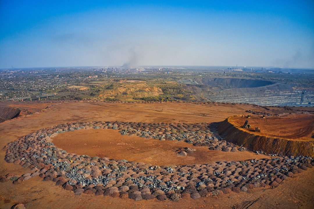 Huge mounds of waste iron ore near the quarry. Belaz trucks driving in mining factory, mine quarry in Ukraine